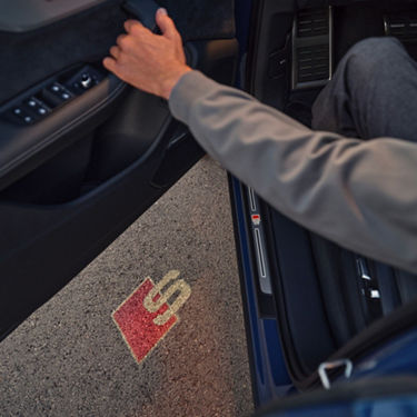 Person exiting a car door over a puddle.