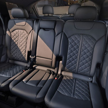 Car interior with quilted leather seats and seat belts.