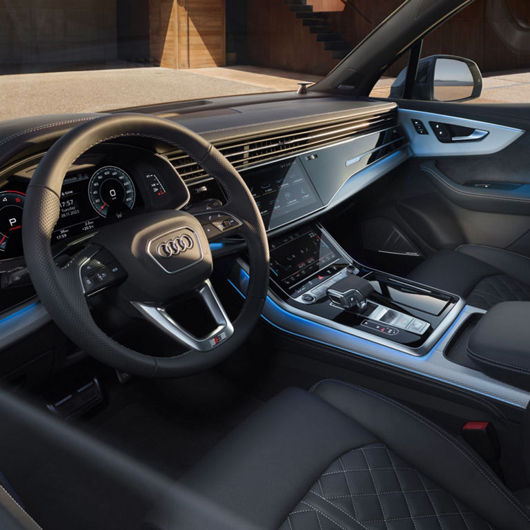 Interior of a car with steering wheel, dashboard, and dual touch screens.