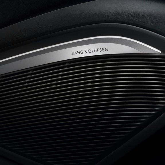 Close-up of a car's speaker grille with "Bang & Olufsen" branding on a sleek black panel.