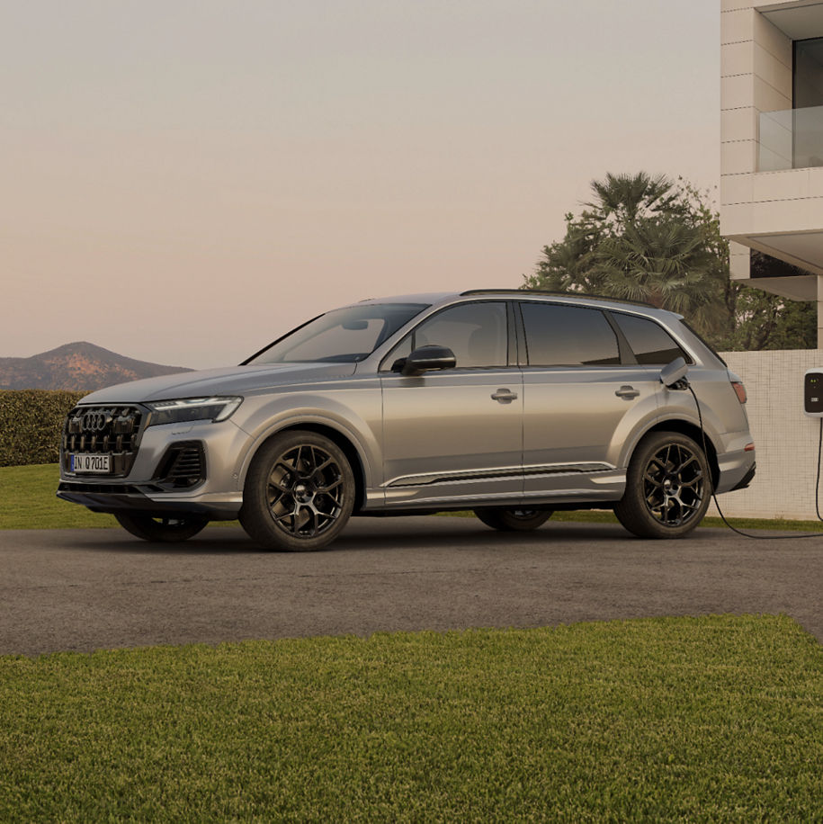 An Audi electric SUV parked in front of a residential house while charging.