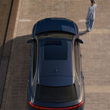 Aerial view of Audi Q3 with woman smartly dressed walking away along brick road.