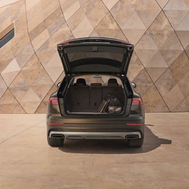 Rear view of opened boot Audi Q8 tfsi e against modern building.