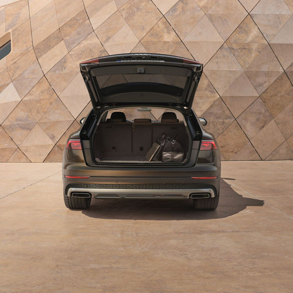 Audi Q8 SUV with boot open park infront of modern building