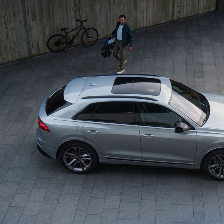 Silver Audi Q8 parked in a spacious warehouse with man approaching.