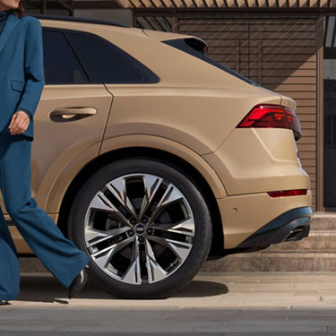   Side rear view of Audi Q8 with suited person walking passed.