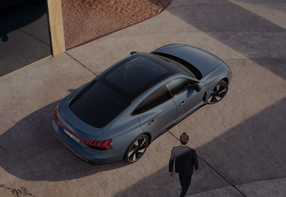 Aerial view of a car parked next to a building with a person approaching it.