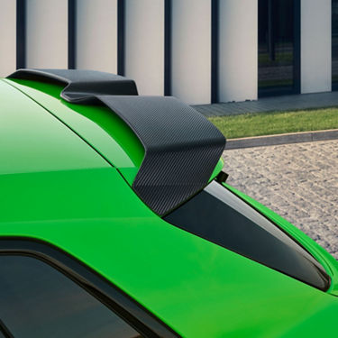  Close-up of a green Audi RS3 Sportback car's rear with a carbon fiber spoiler.