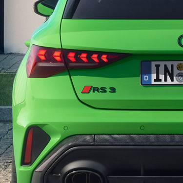  Rear view of a bright green Audi RS3 car with distinctive taillights and a black diffuser.