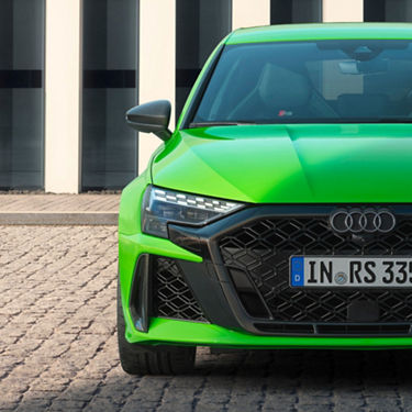  Bright green Audi RS3 sportscar parked in front of a striped building.