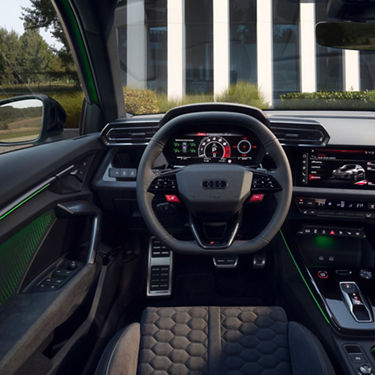 Interior view of an Audi RS3 Sportback car with a digital dashboard and center console, and a hexagon pattern on seats. 