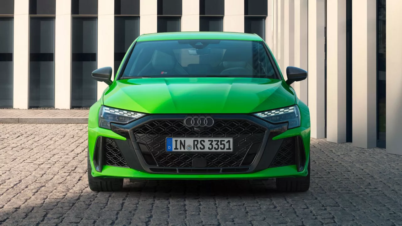 Bright green Audi RS3 car parked in front of a building with striped facade.