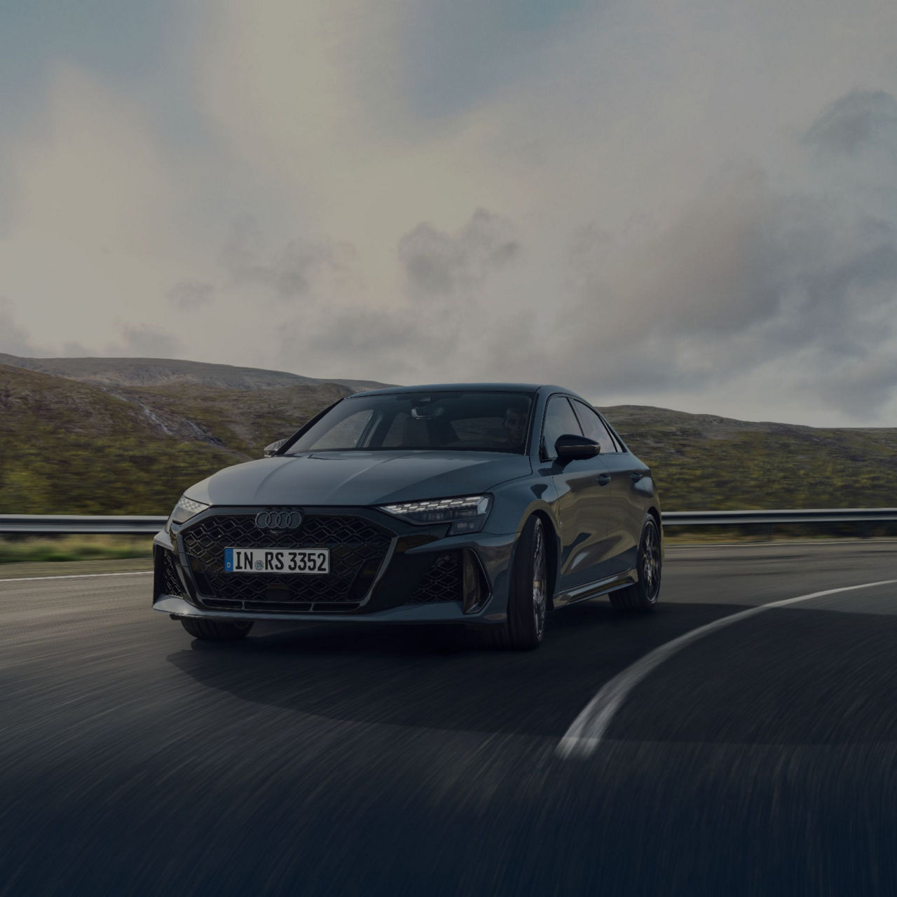 Audi RS3 Sportback driving on a highway with a cloudy sky background.