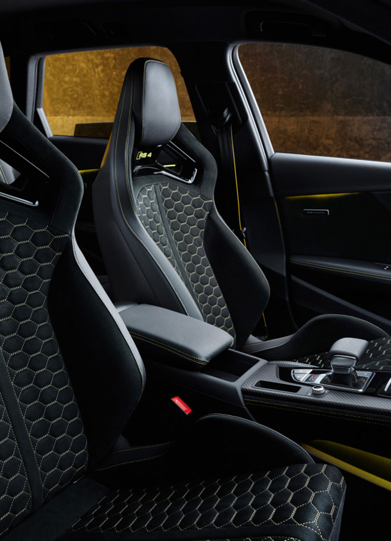Interior of a car with stylish black sports seats and yellow stitching.