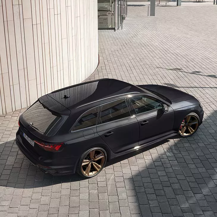 A black car parked on a patterned paving with cream-coloured curved walls.