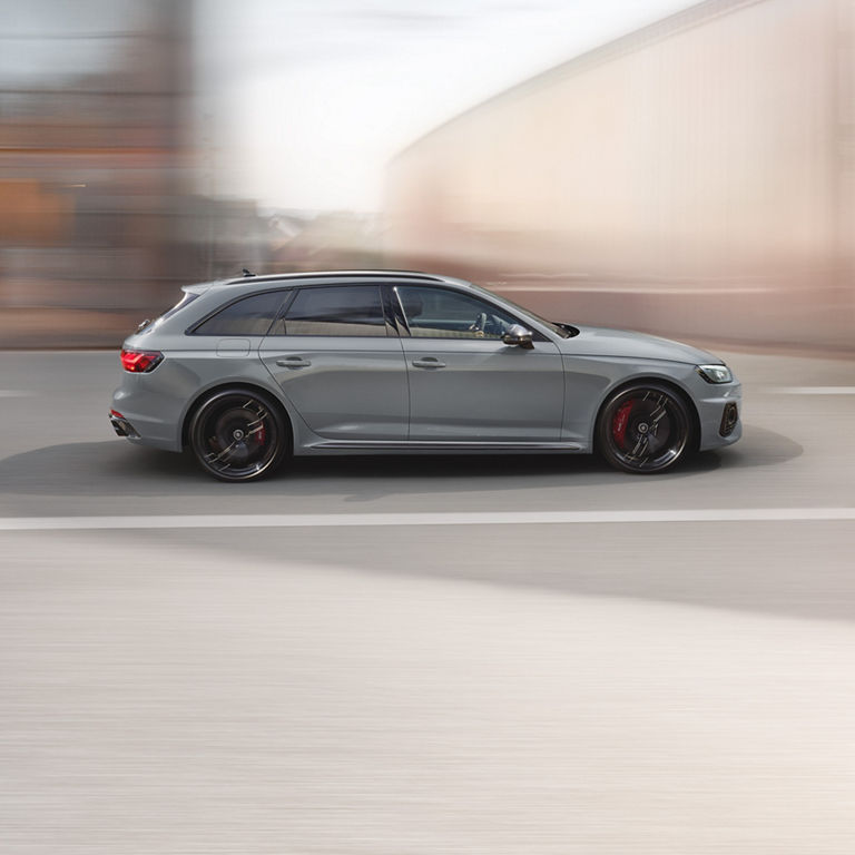 A grey car in motion on an urban road, with a blurred background indicating speed.