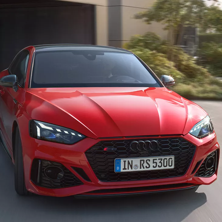 Red Audi RS5 Coupe in motion on a road.