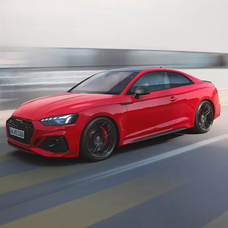 Red Audi RS5 Coupe in motion on a blurred background.