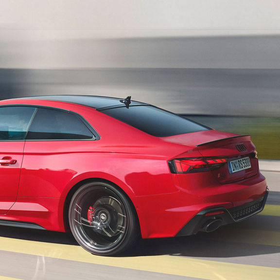 Red RS5 coupe in motion on a blurred background, emphasising speed.