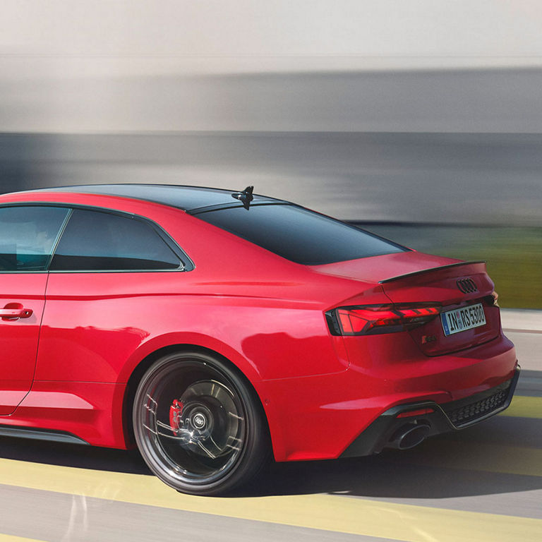 Red RS5 coupe in motion on a blurred background, emphasising speed.