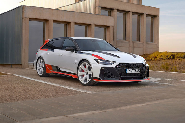 A white Audi with black and red accents parked in front of a modern building.