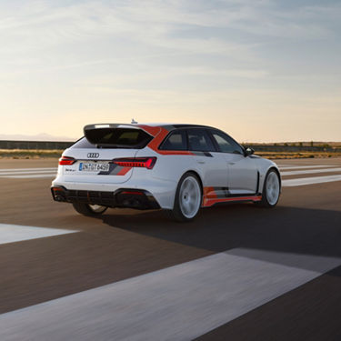 A white Audi RS6 Avant GT driving on a highway at dusk.