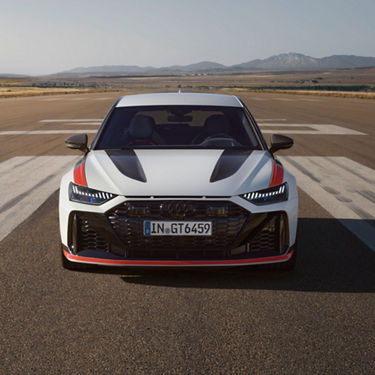 A white Audi car on a tarmac with mountains in the distance.