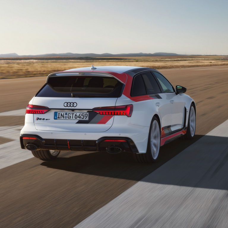 White Audi driving on road with blurred background, highlighting speed.