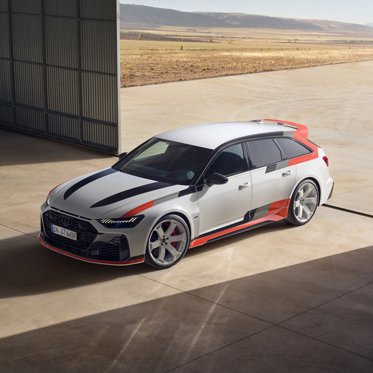 Car with a dynamic black, white, and red livery, parked outside near containers.