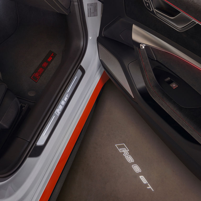 Car interior with detailed stitching, "RS 6 GT" branding, and red accents.