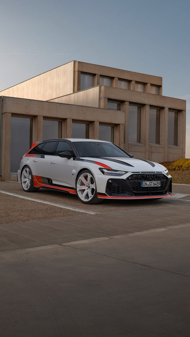 A white Audi with black and red accents parked in front of a modern building.