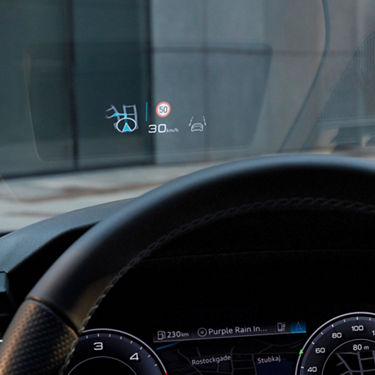 Heads-up display in a car showing speed, navigation, and lane assist icons.