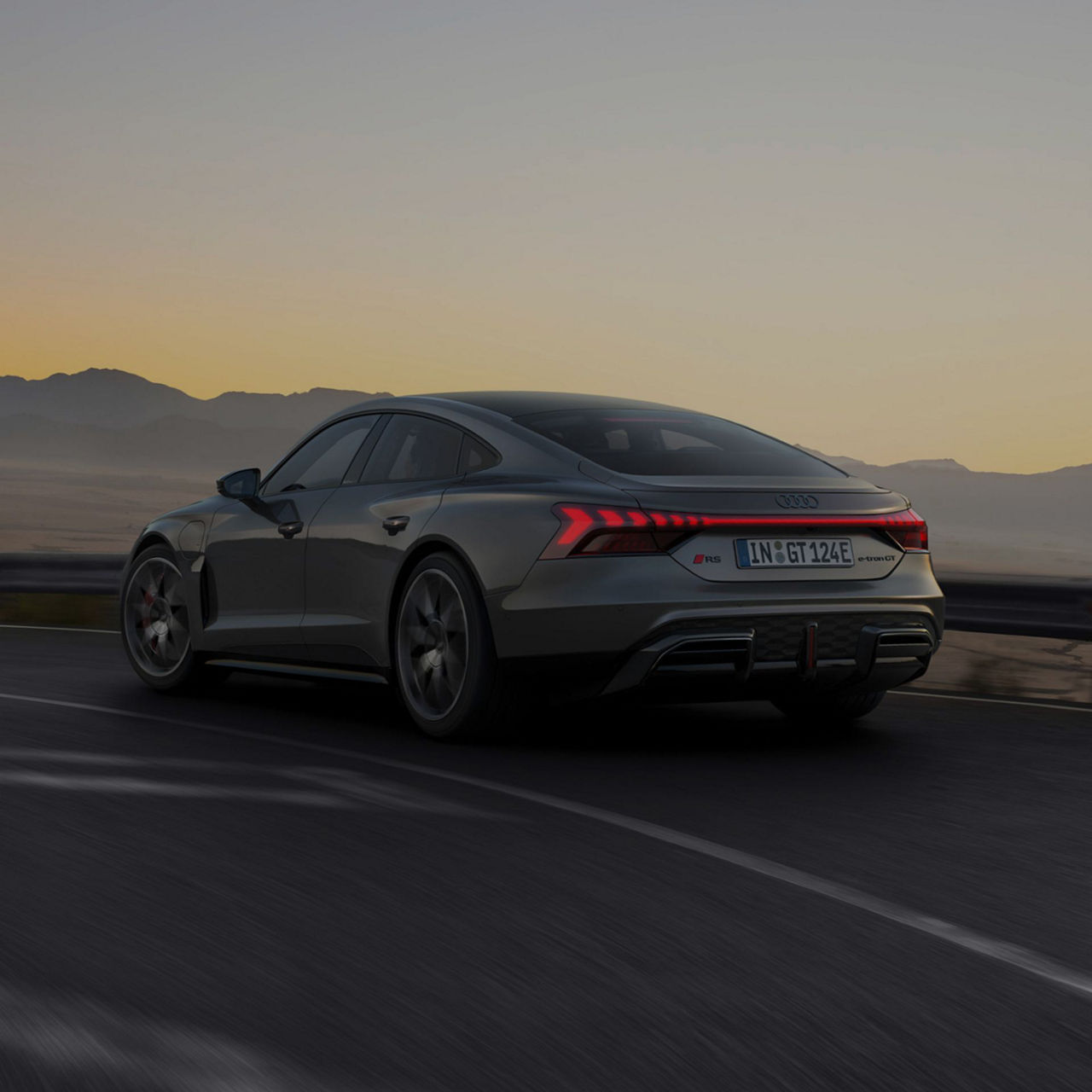 Audi RS e-tron GT car driving at dusk with mountains in the background.