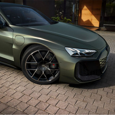 A matte green Audi car parked on a cobblestone driveway.