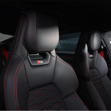 Audi RS e-tron GT Performance car interior with black leather sports seats featuring red stitching and RS logo.