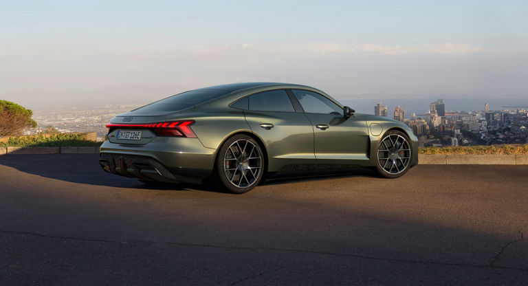 A green Audi electric sedan parked with a cityscape in the background.