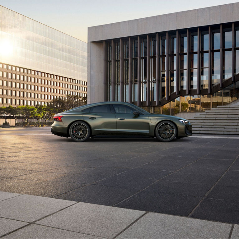 A modern sedan parked on pavement with contemporary buildings in the background.