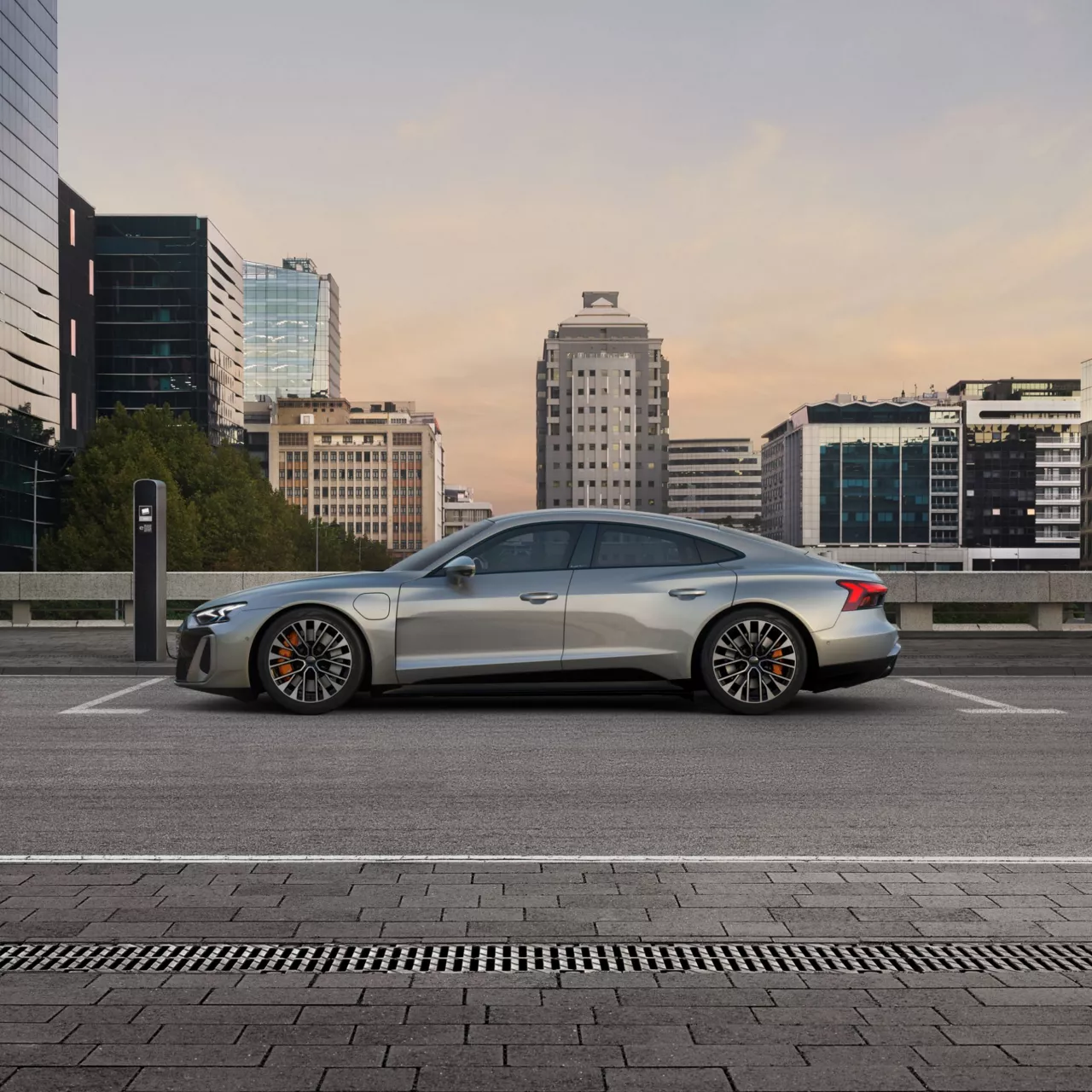 Silver sedan charging at an urban electric vehicle station with skyscrapers in the background.