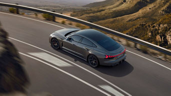 A grey Audi driving on a highway with mountainous scenery in the background.