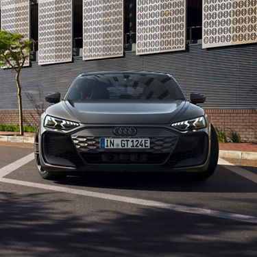 Audi electric car parked on a street with a patterned building in the background.