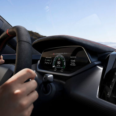 Driver's POV of a modern car dashboard display indicating speed and battery status.