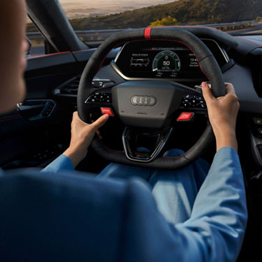Driver's hands on an Audi steering wheel with dashboard view.