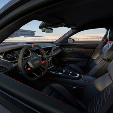 Interior of an Audi vehicle showcasing the steering wheel, dashboard, and leather seats with red stitching.