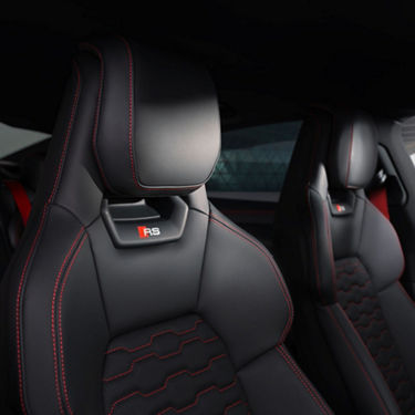 Audi car interior with black and red detailed sport seats marked 'RS'.