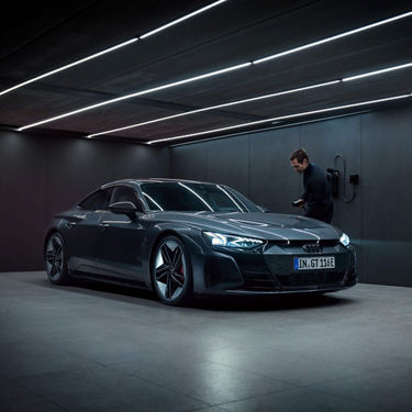 A sleek dark-colored electric car parked in a modern garage with ambient lighting.