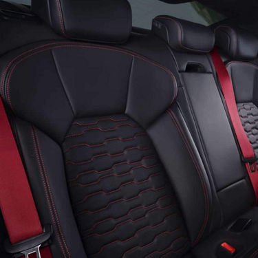 Car seat with black leather, red stitching, and textured pattern.