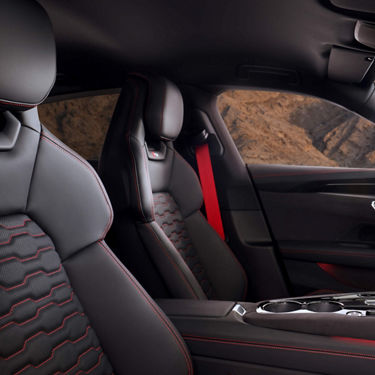 Car interior with leather seats featuring red stitching and accents.