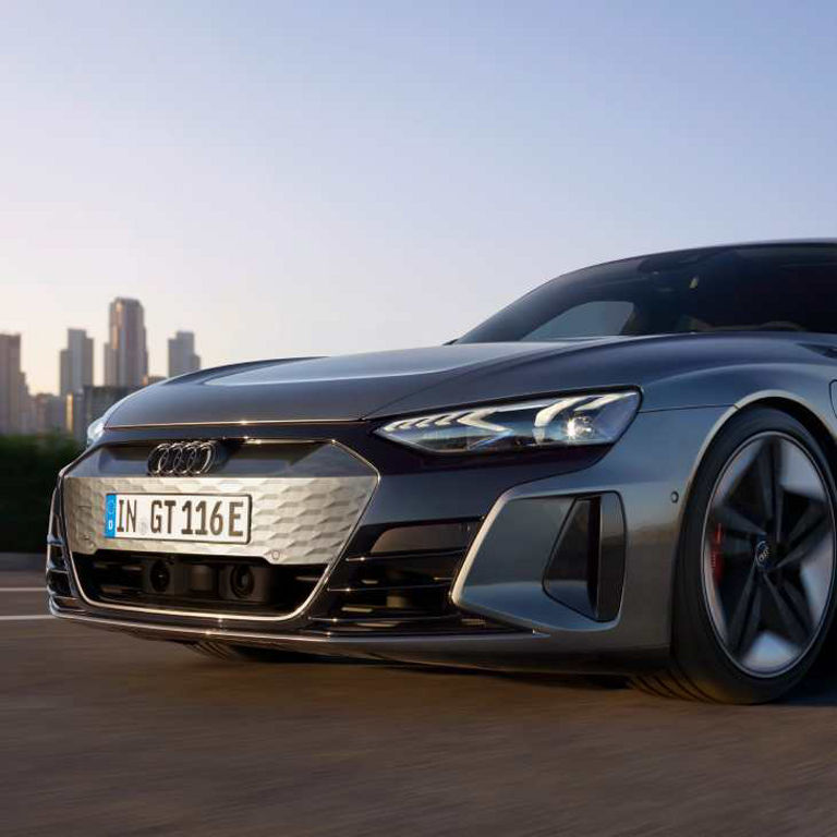 Audi electric sports car driving with city skyline in the background.