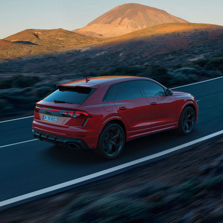 Red Audi RS Q8 Performance travelling along an open mountainous road.