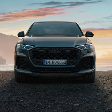 Audi RS Q8 on gravel path with mountainous misty background.